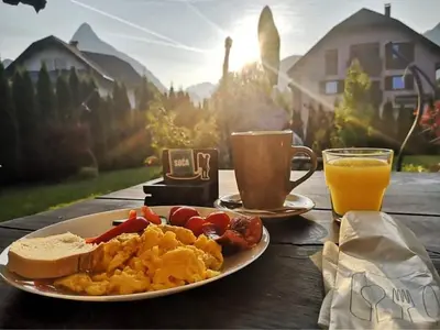 a plate of breakfast food and a cup of orange juice at Hostel Soča Rocks in Bovec