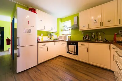 a kitchen with white cabinets and green walls at Hostel Soča Rocks in Bovec