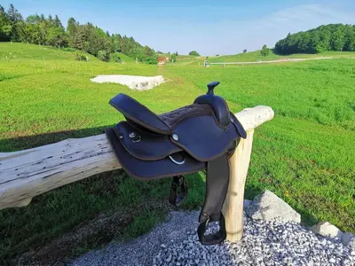 a black cow saddle sitting on a wooden fence at Cowboy's Land in Višnja Gora