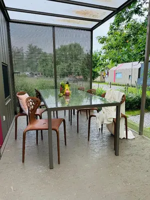 a glass table and chairs on a patio at MAGNOLIA HOUSE by the RIVER XL in Metlika
