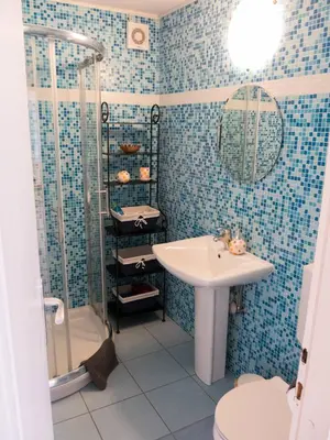 a blue tiled bathroom with a sink and a shower at Apartment Otava in Šempas