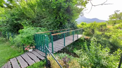 a wooden walkway with a green railing in a garden at Apartment Otava in Šempas