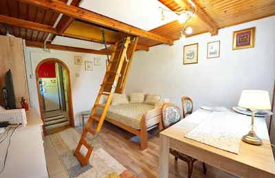 a room with a bed and a desk and a ladder at Emerald Bell Cottage - Smaragdni Zvonček in Gomilsko