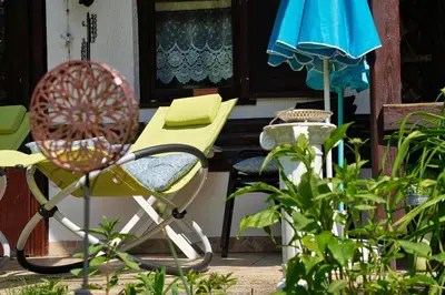 a patio with a table and a chair and an umbrella at Emerald Bell Cottage - Smaragdni Zvonček in Gomilsko