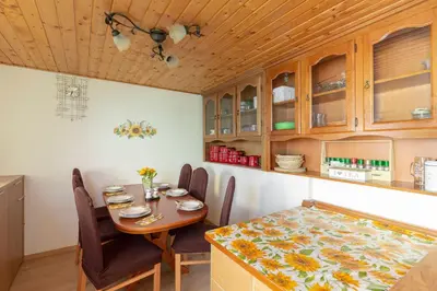 a dining room with a table and chairs and a kitchen at Sunflower House with Jacuzzy and Sauna in Vitanje