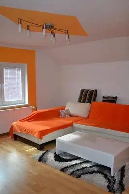 a bedroom with an orange bed and a white couch at Apartma ob potoku in Luče