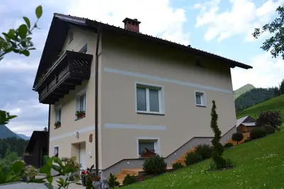 a white house with a balcony on a hill at Apartma ob potoku in Luče