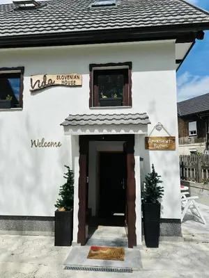 a small white building with a door and two potted plants at Slovenian House Vida in Bled