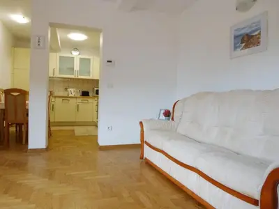 a living room with a white couch and a kitchen at Apartment Jalps 2 in Bohinj