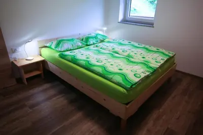 a bed in a room with a green blanket on it at Apartma Gorski razgled in Srednja Vas v Bohinju
