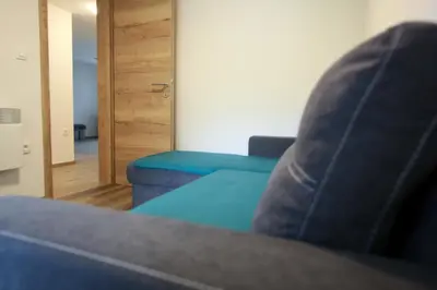 a living room with a couch and a blue chair at Apartma Gorski razgled in Srednja Vas v Bohinju
