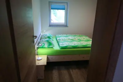 a small bed in a room with a window at Apartma Gorski razgled in Srednja Vas v Bohinju