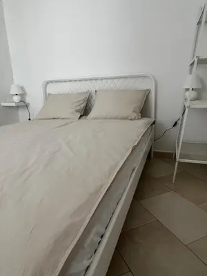 a white bed with white sheets and pillows on it at Guesthouse 45 in Dutovlje
