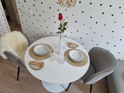 a white dining room table with chairs and a red rose at Apartma Larisa in Bled