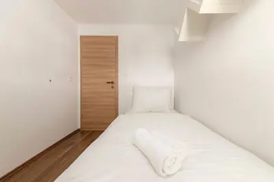 a small bedroom with a bed with white sheets at Frida's Place Ljubljana in Ljubljana