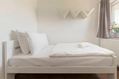 a white bed with white sheets and pillows in a room at Frida's Place Ljubljana in Ljubljana