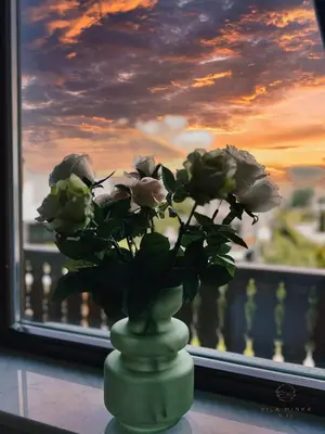 a green vase with roses in front of a window at Vila Minka Bled - Perfect Family Vacation Home in Bled