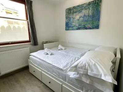 a bedroom with a bed with white sheets and a window at Nina's Place in Bled