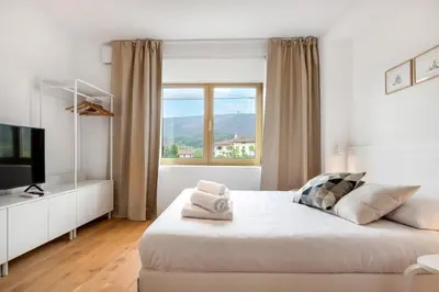 a white bedroom with a large bed and a window at Modern holiday home with terrace close to Nova Gorica in Miren