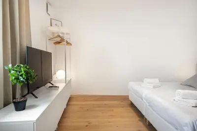 a white bedroom with a bed and a desk with a tv at Modern holiday home with terrace close to Nova Gorica in Miren