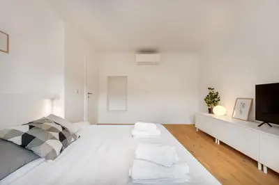 a white bedroom with a bed and a tv at Modern holiday home with terrace close to Nova Gorica in Miren