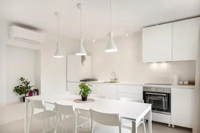a white kitchen with a white table and chairs at Modern holiday home with terrace close to Nova Gorica in Miren