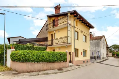 a yellow house with a balcony on a street at Modern holiday home with terrace close to Nova Gorica in Miren