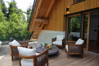 a patio with a table and chairs and glass doors at The Vila Bled Premium Luxury Retreat in Bled