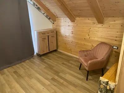 a room with a chair and a wooden wall at Posestvo Tmžek in Bovec