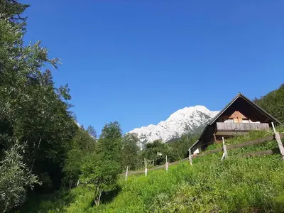 a cabin on a hill with a mountain in the background at Camping & Glamping Grintovec in Preddvor