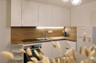 a kitchen with white cabinets and a sink and a refrigerator at Esti’s Oasis in Ljubljana