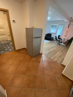 a kitchen with a refrigerator and a living room at Ada Apartment in Ljubljana