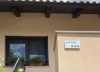 a sign on a building with plants on a window at Greg's Rooms in Ilirska Bistrica