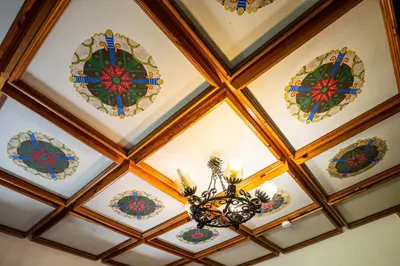 a coffered ceiling with stained glass windows and a chandelier at Traditional homestead Guhar in Radovna in Mojstrana