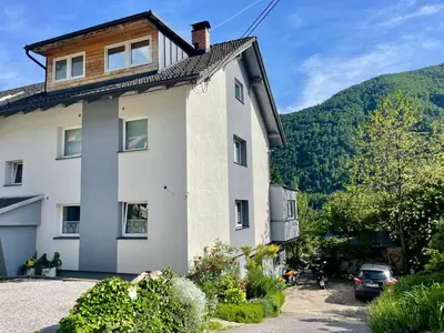 a white house with a mountain in the background at Apartma Zeus in Jesenice