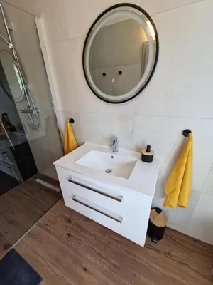 a bathroom with a white sink and a mirror at Medeni Apartma in Pivka