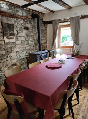 a dining room with a large red table and chairs at Casa di Volce - 1801 Stone House in Tolmin