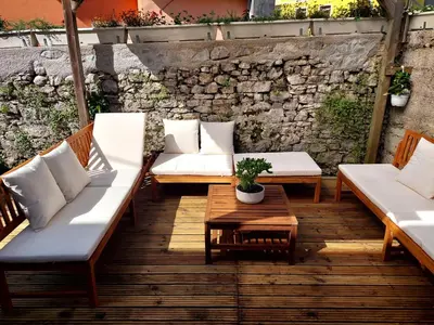 a patio with couches and a table and a stone wall at Casa di Volce - 1801 Stone House in Tolmin
