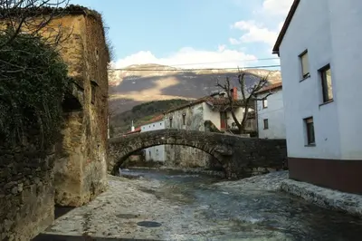 an alley in a town with a stone bridge at Guest House Žerjal in Podnanos