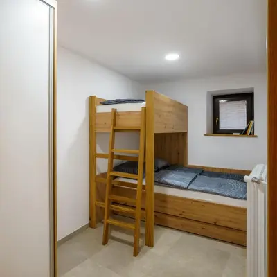 a bunk bed with a ladder in a room at Guest House Žerjal in Podnanos
