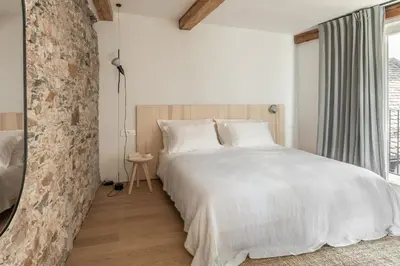 a bedroom with a white bed and a stone wall at April1550 Boutique Hotel in Ljubljana