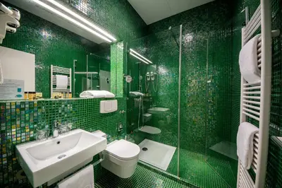 a green tiled bathroom with a sink and a shower at Rimske Terme Resort - Hotel Sofijin dvor in Rimske Toplice