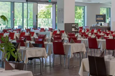 a room full of tables and chairs with red chairs at Rimske Terme Resort - Hotel Sofijin dvor in Rimske Toplice
