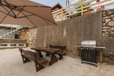 a picnic table with an umbrella and a grill at Apartments Ribnica in Bohinj
