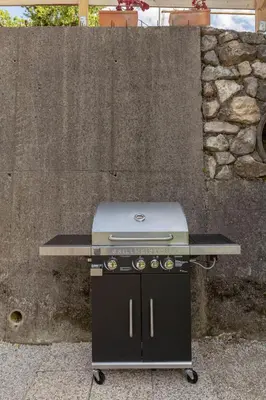 a grill sitting in front of a stone wall at Apartments Ribnica in Bohinj
