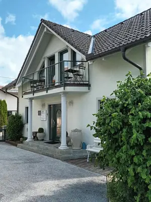a white house with a balcony and a porch at Apartment Jovan in Bled