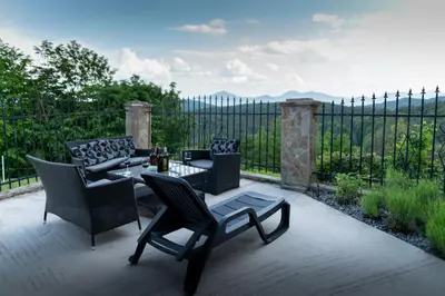 a patio with chairs and a table and a fence at VILA HELENA in Velenje