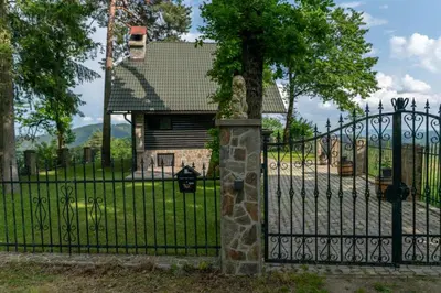 a black fence with a tree in front of a house at VILA HELENA in Velenje