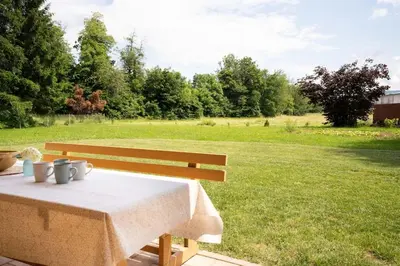 a wooden bench with a table in a field at A Nest Under the Karawanks in Žirovnica