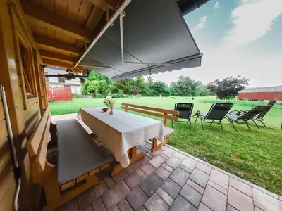 a patio with a table and chairs and a field at A Nest Under the Karawanks in Žirovnica